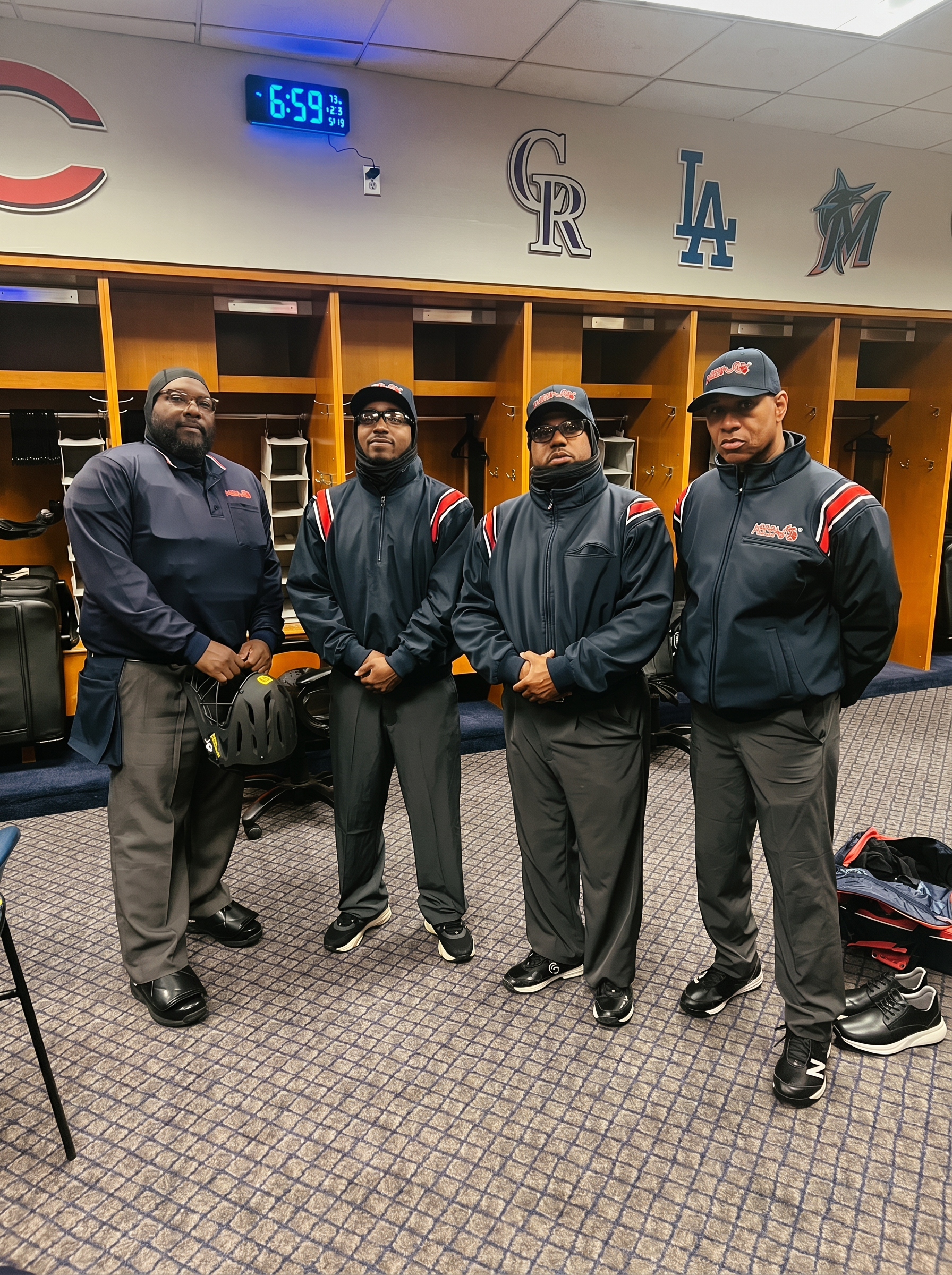 Four young referees gathered together in a locker room with team logos on the wall
